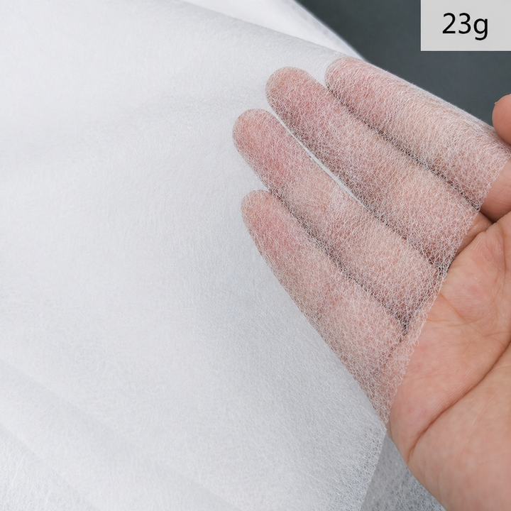 Close-up of a hand holding a Fusible Interlining Fabric with a visible weight label &