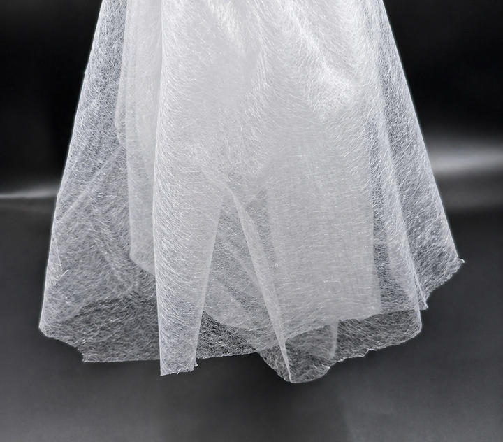 Close-up of a white Fusible Interlining Fabric with a textured pattern on a dark background