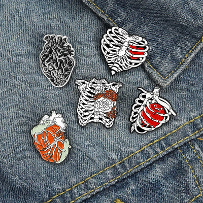 Five anatomical-themed pins on a denim jacket