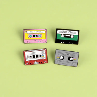 Four colorful cassette tape-shaped pins on a light green background