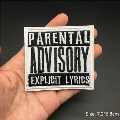 Hand holding a 'Parental Advisory Explicit Lyrics' patch against a dark background