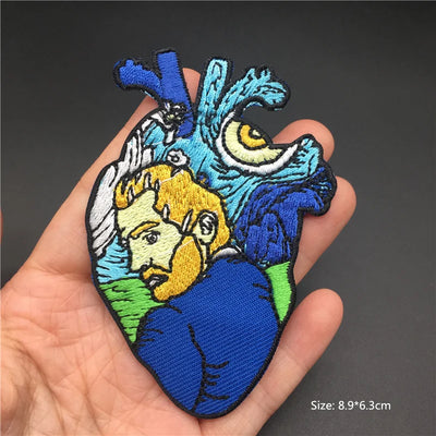 Embroidered patch of a heart with a face design held in a hand against a dark background