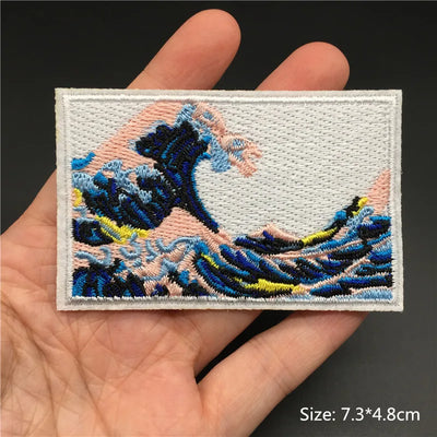 Embroidered patch of a wave design held in a hand with a dark background