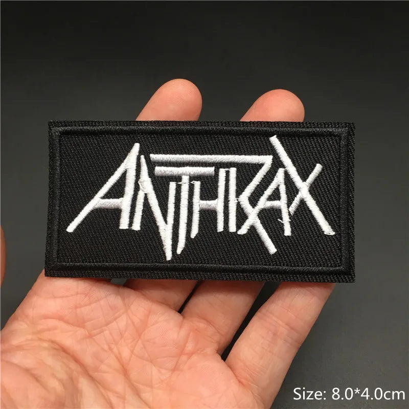 Black patch with 'ANTICIDAX' text held in a hand against a dark background