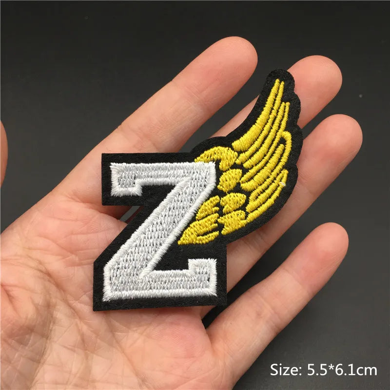 Patch with letter 'Z' and wings held in a hand against a dark background