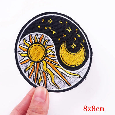 Embroidered patch with sun and moon design held by a hand on a white background