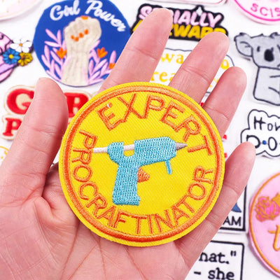 Hand holding a yellow patch with 'Expert Procrastinator' text and a drill icon, surrounded by other colorful patches.
