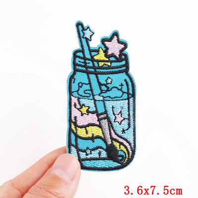 Embroidered patch of a jar with stars and a straw on a white background