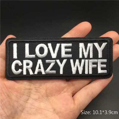 Embroidered patch with 'I LOVE MY CRAZY WIFE' text held in a hand against a dark background.