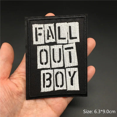 Patch with 'Fall Out Boy' text held in a hand against a dark background