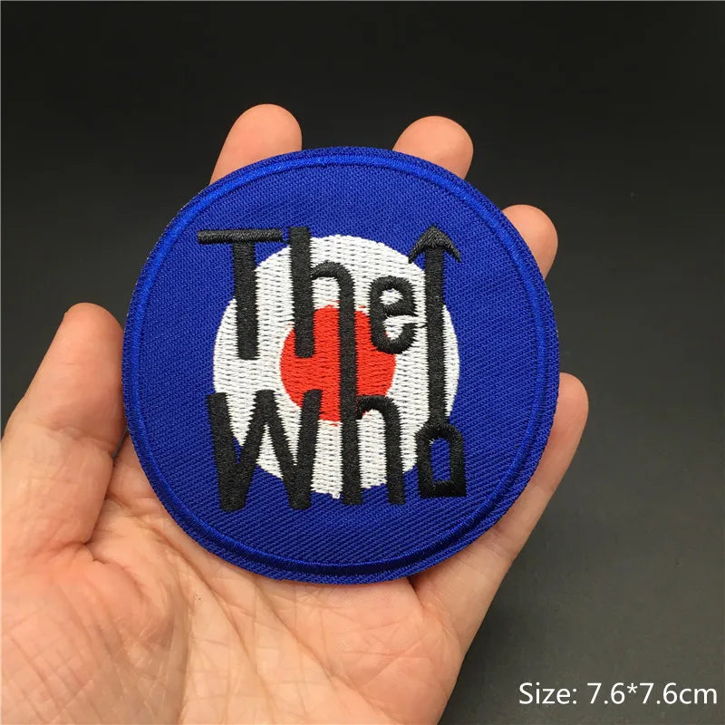 Circular patch with 'The Who' logo held in a hand against a dark background