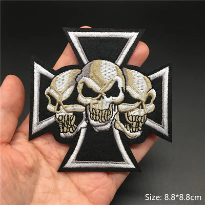 Skull patch with cross design held in a hand, on a dark background