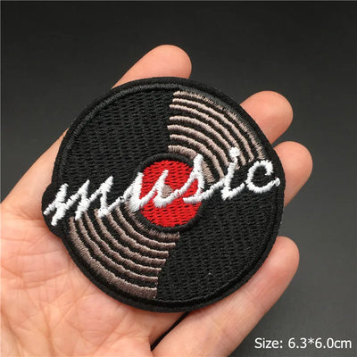 Embroidered patch with vinyl record design held in a hand against a dark background