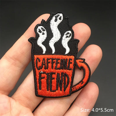 Embroidered patch of a coffee cup with steam and 'CAFFEINE FRIEND' text held in hand.