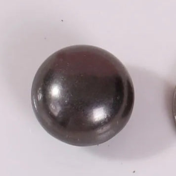 Black spherical object next to a Chinese coin on a white background