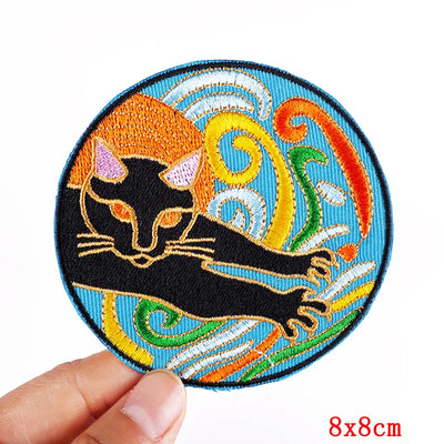 Embroidered patch with a black cat design held by a hand on a white background