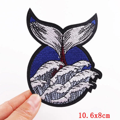Embroidered patch with whale design held by a hand on a white background