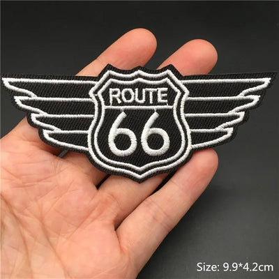 Route 66 patch with wings held in a hand against a dark background