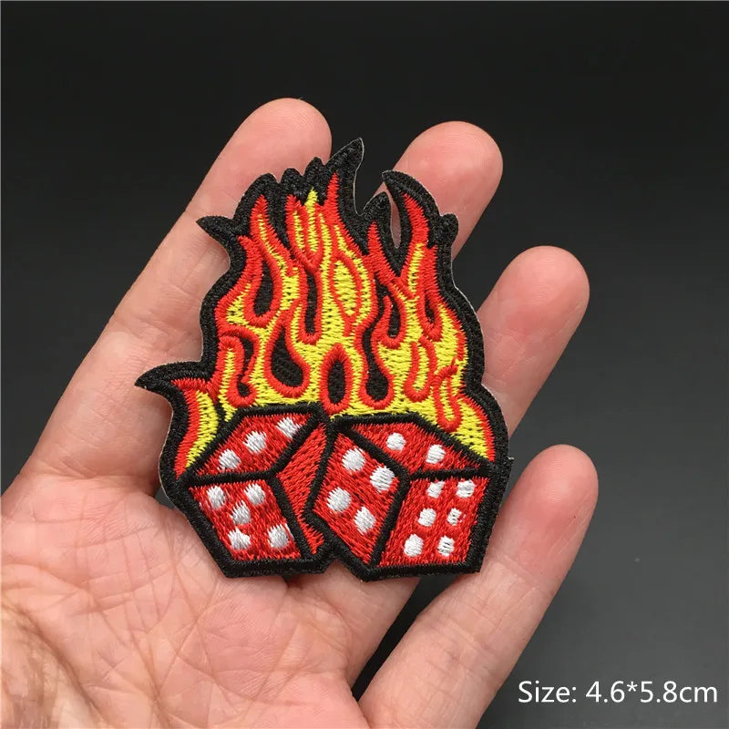 Flame and dice design patch held in a hand with a dark background