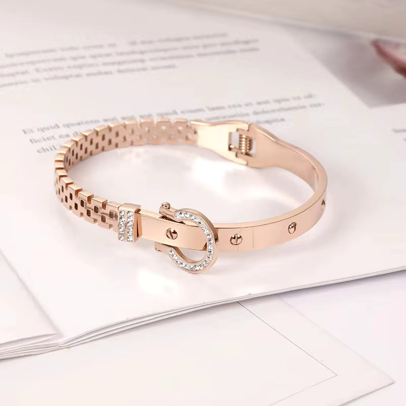 Rose gold bracelet with diamond accents on a white surface