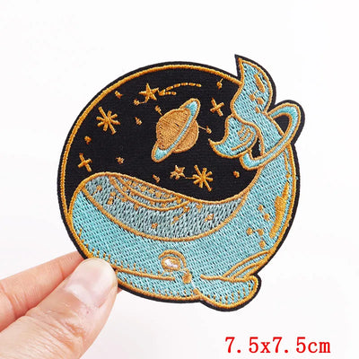 Embroidered patch with space design held by a hand, size 7.5x7.5cm.