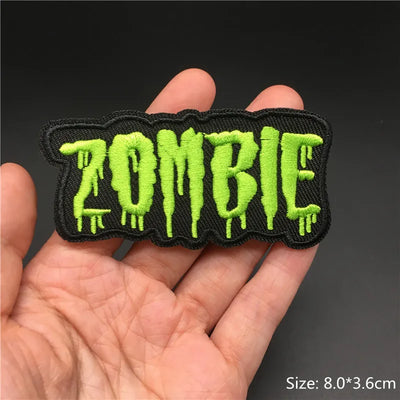 Embroidered patch with 'ZOMBIE' text held in a hand against a dark background