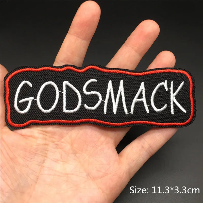 Patch with 'GODSMACK' text held in a hand against a dark background