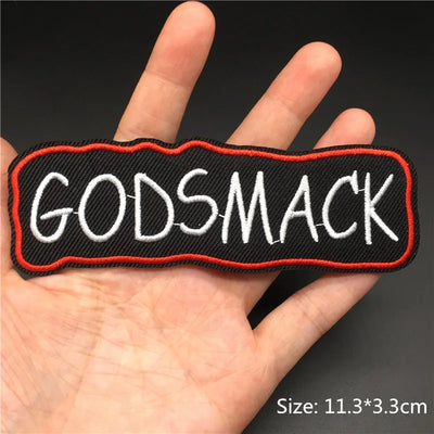 Patch with 'GODSMACK' text held in a hand against a dark background