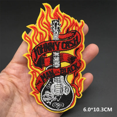 Embroidered patch with guitar design and 'Man in Black' text held in a hand against a dark background.