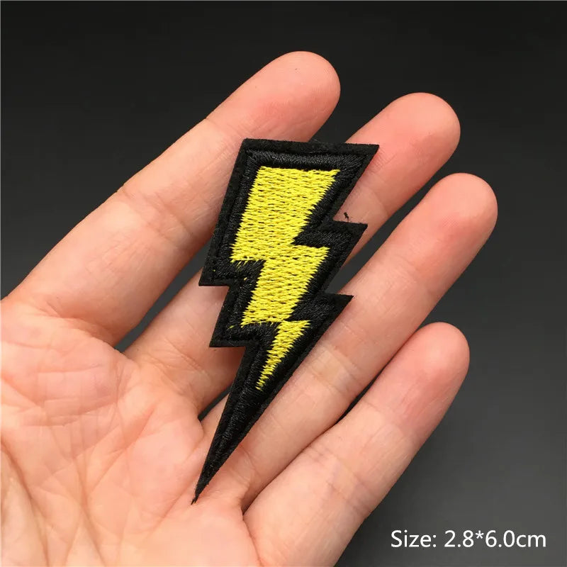 Yellow lightning bolt patch held in a hand with a dark background