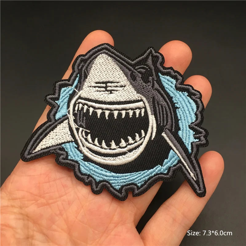 Shark patch held in a hand with a dark background
