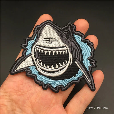 Shark patch held in a hand with a dark background