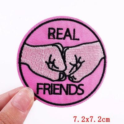 Pink patch with 'Real Friends' text and a hand holding it