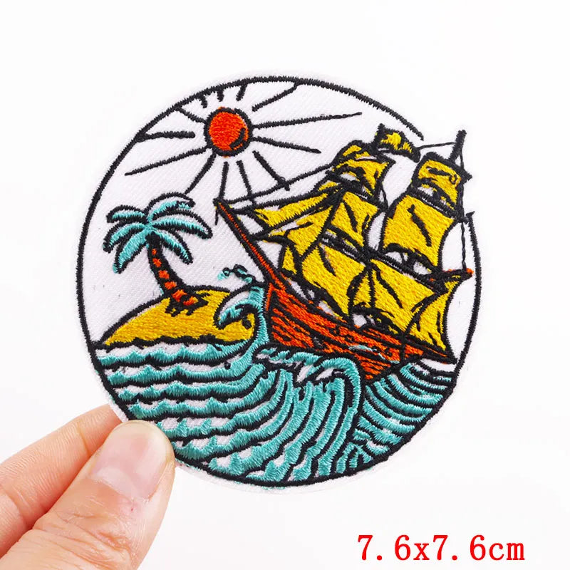 Embroidered patch with a ship, palm tree, and sun on a white background