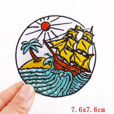 Embroidered patch with a ship, palm tree, and sun on a white background
