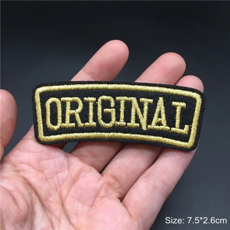 Embroidered patch with 'ORIGINAL' text held in a hand against a dark background