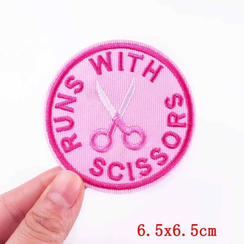 Pink patch with scissors and text held by a hand on a white background