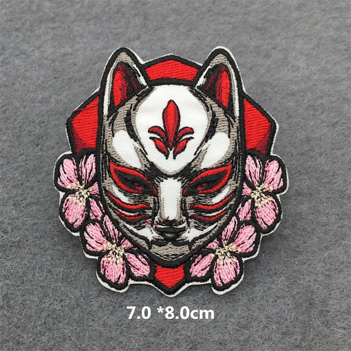 Embroidered patch of a fox mask with red and white design on a gray background