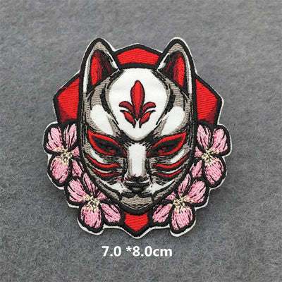 Embroidered patch of a fox mask with red and white design on a gray background