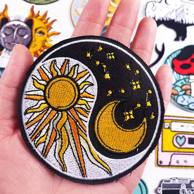 Patch with sun and moon design held in a hand, surrounded by other patches.