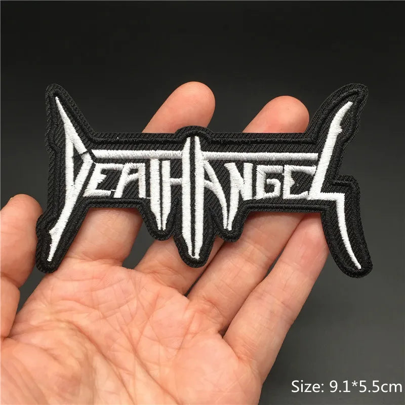 Embroidered patch with 'DEATH ANGEL' text held in a hand against a dark background