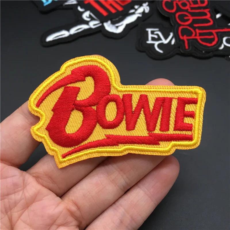 Embroidered patch with 'Bowie' in red on yellow background held in hand