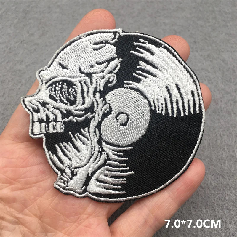 Skull and yin yang patch held in a hand with a gray background
