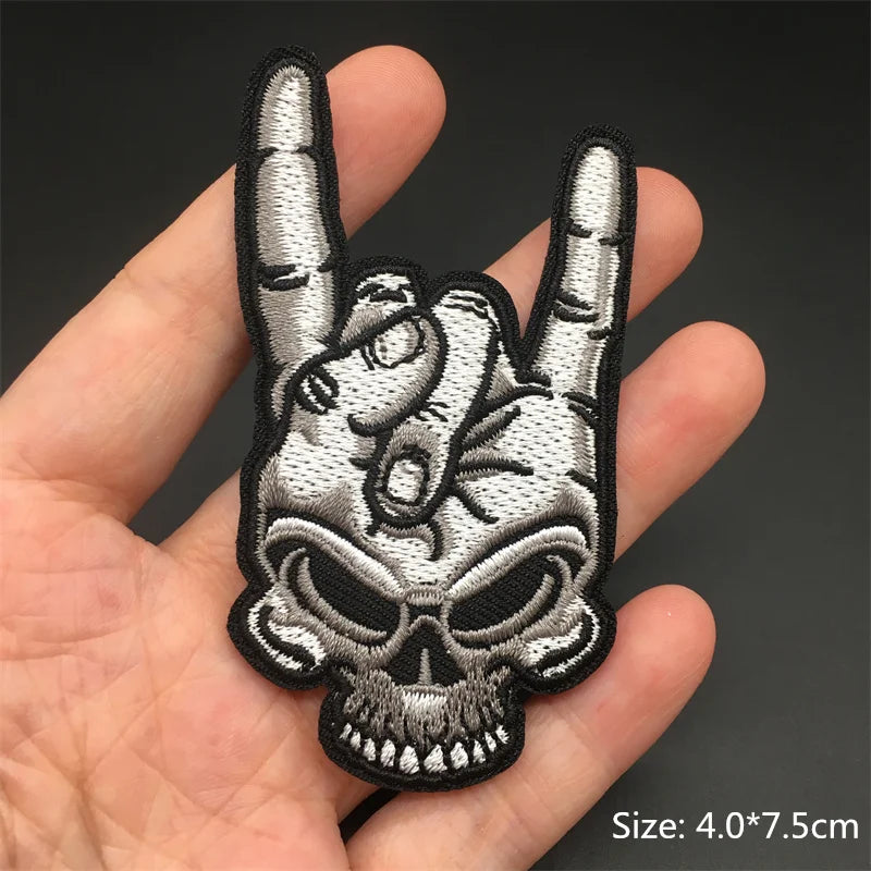Embroidered patch of a hand making a rock sign with a skull design held in a hand.