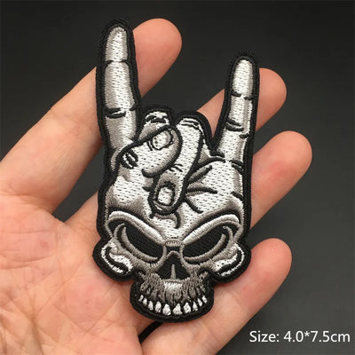 Embroidered patch of a hand making a rock sign with a skull design held in a hand.