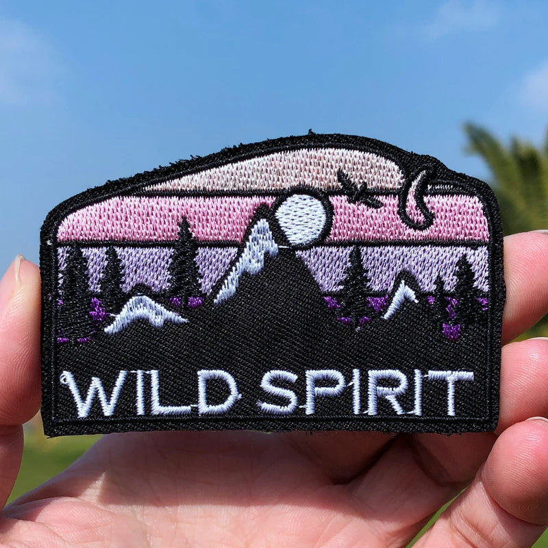 Patch with 'Wild Spirit' design held in a hand against a blue sky.