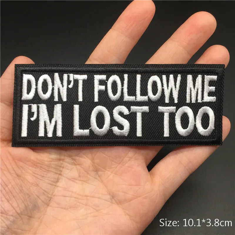 Embroidered patch with 'DON'T FOLLOW ME I'M LOST TOO' text held in a hand.