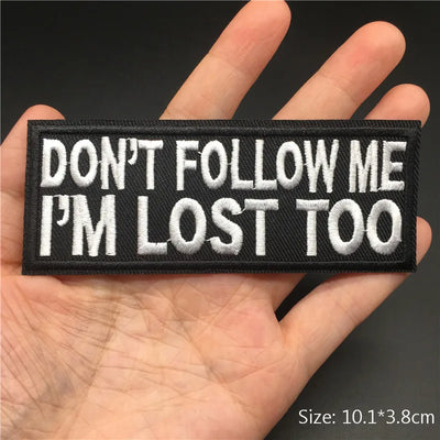 Embroidered patch with 'DON'T FOLLOW ME I'M LOST TOO' text held in a hand.