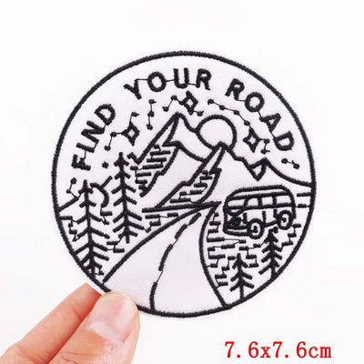 Circular patch with 'Find Your Road' text and mountain design held by a hand on a white background.