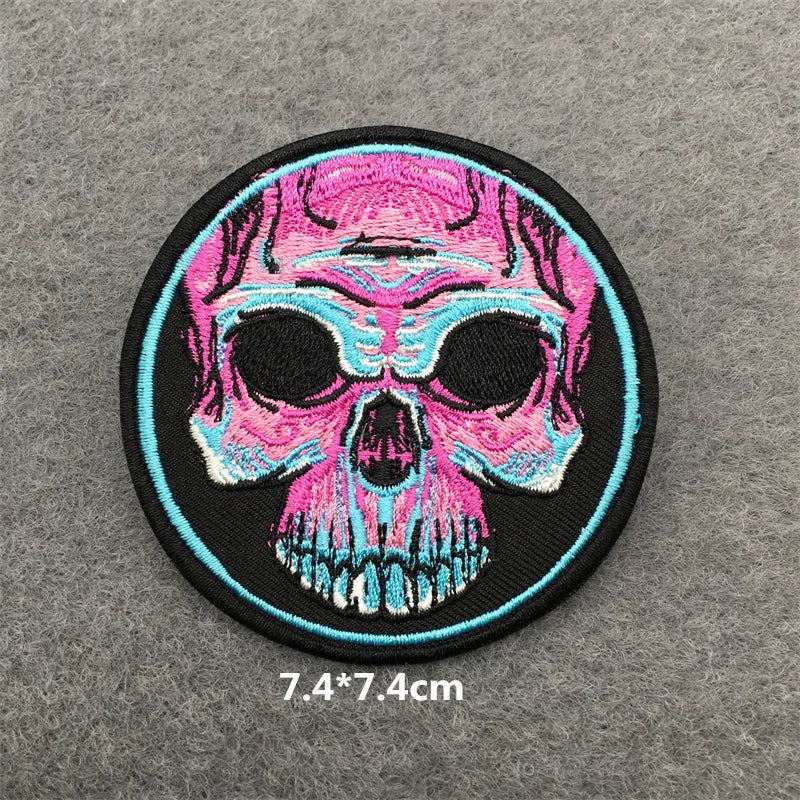 Circular patch with a pink and blue skull design on a gray background